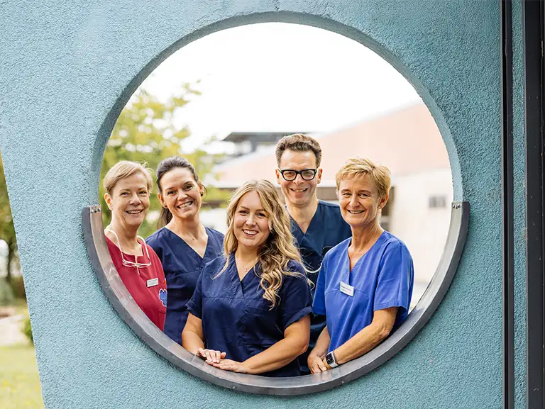 Teamfoto Praxisgemeinschaft Dr. Reich und Dr. Weinmeister, Außenbereich, rundes Fenster
