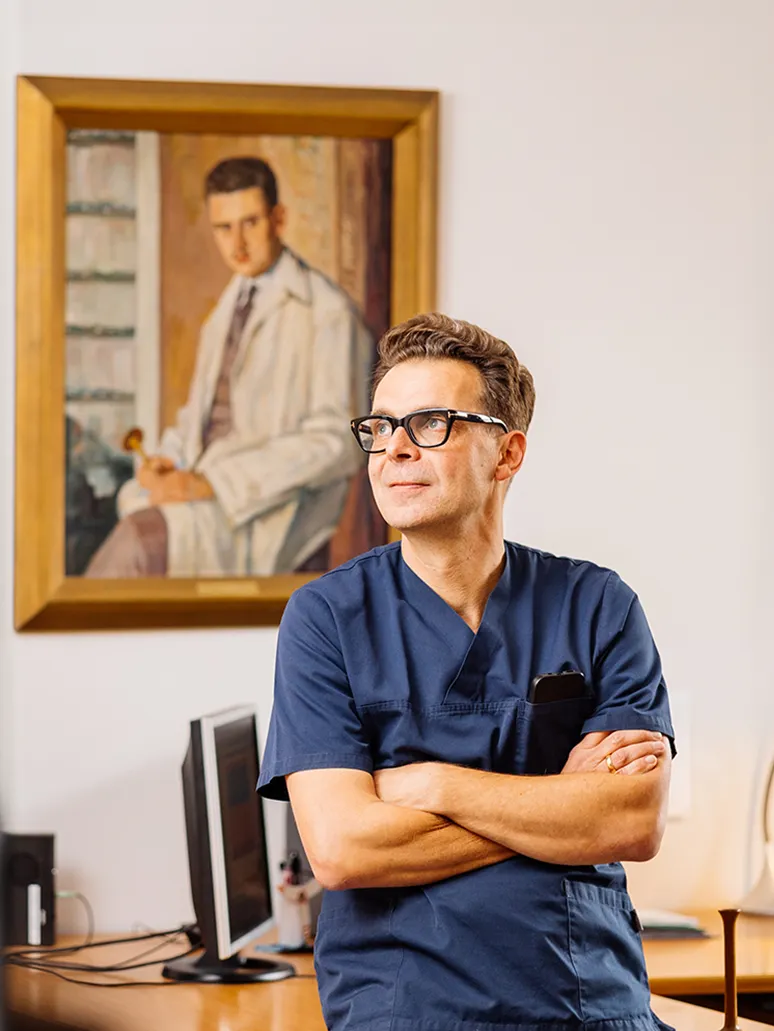 Herr Dr. Reich Portrait in seiner Praxis mit Bild vom Vater der ebenfalls Mediziner war